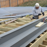 Image showing "Worker installing gray deck boards on a wooden frame.