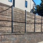 Wooden privacy fence with planks mounted on a stone.