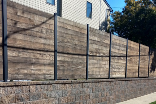Wooden privacy fence with planks mounted on a stone.
